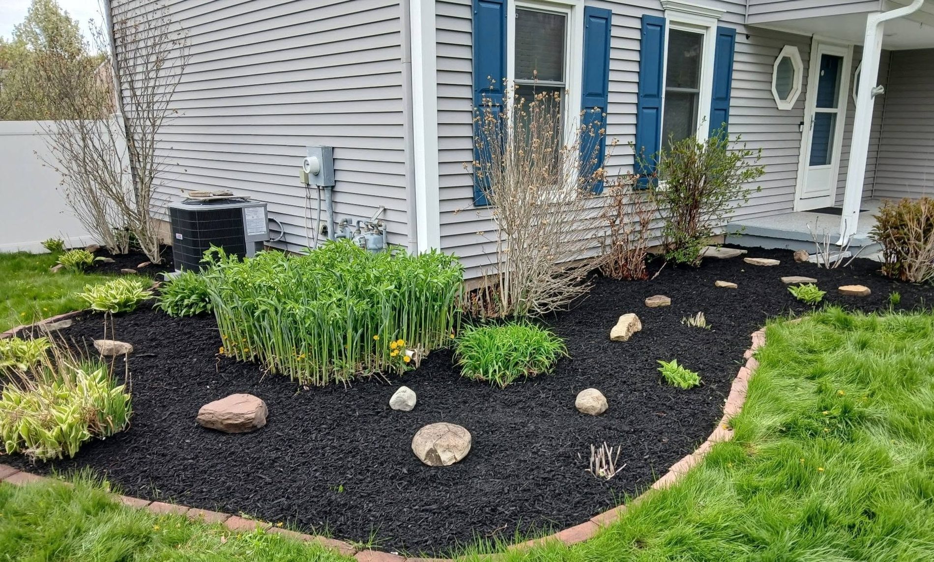 A freshly mulched garden bed with crisp edging beside a Rochester home